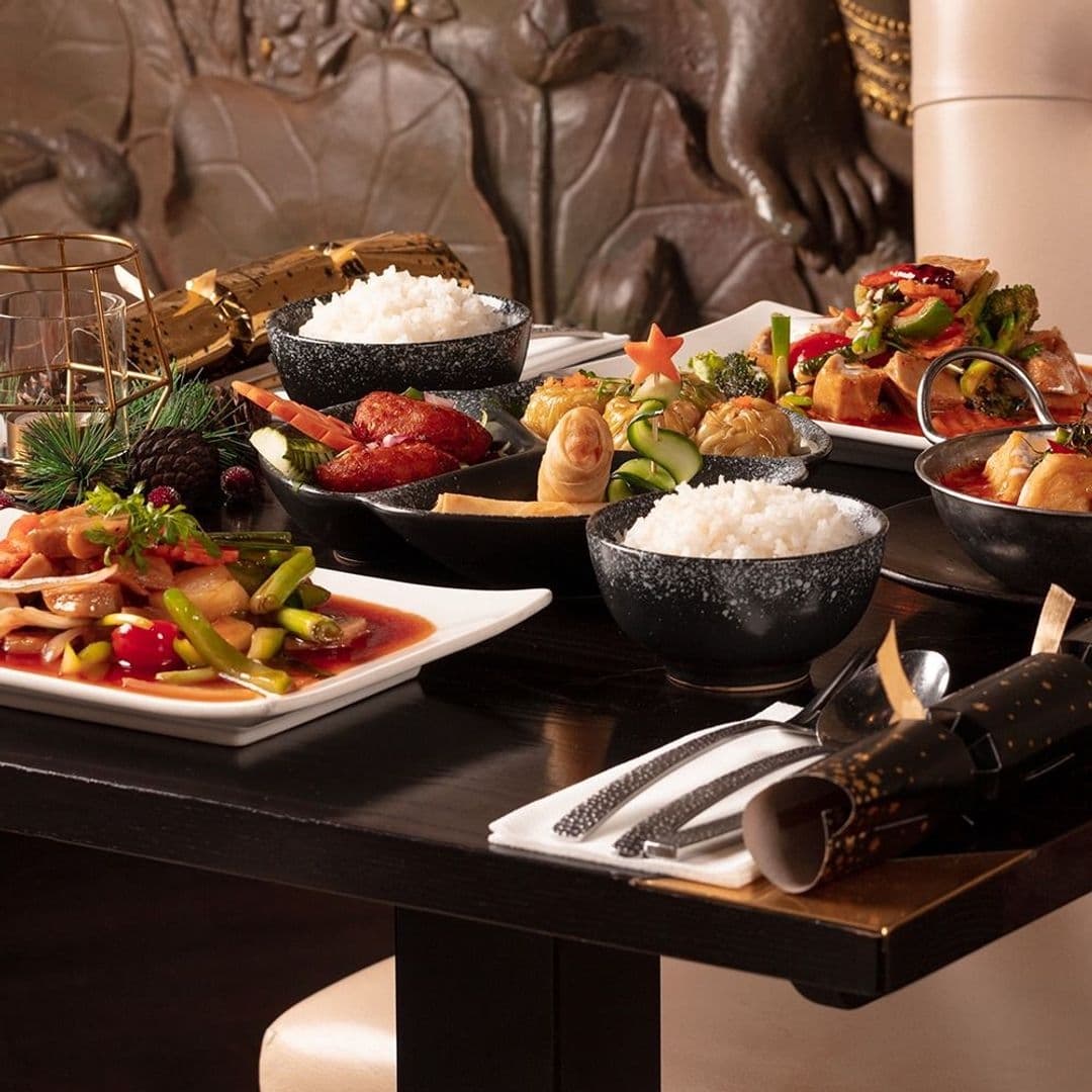 Sukhothai Chapel Allerton Thai Cuisine Dining Experience Assorted Thai dishes on a table at Sukhothai Chapel Allerton, featuring bowls of white rice, spring rolls, and various meat and vegetable entrees, with elegant tableware on a dark wooden table.