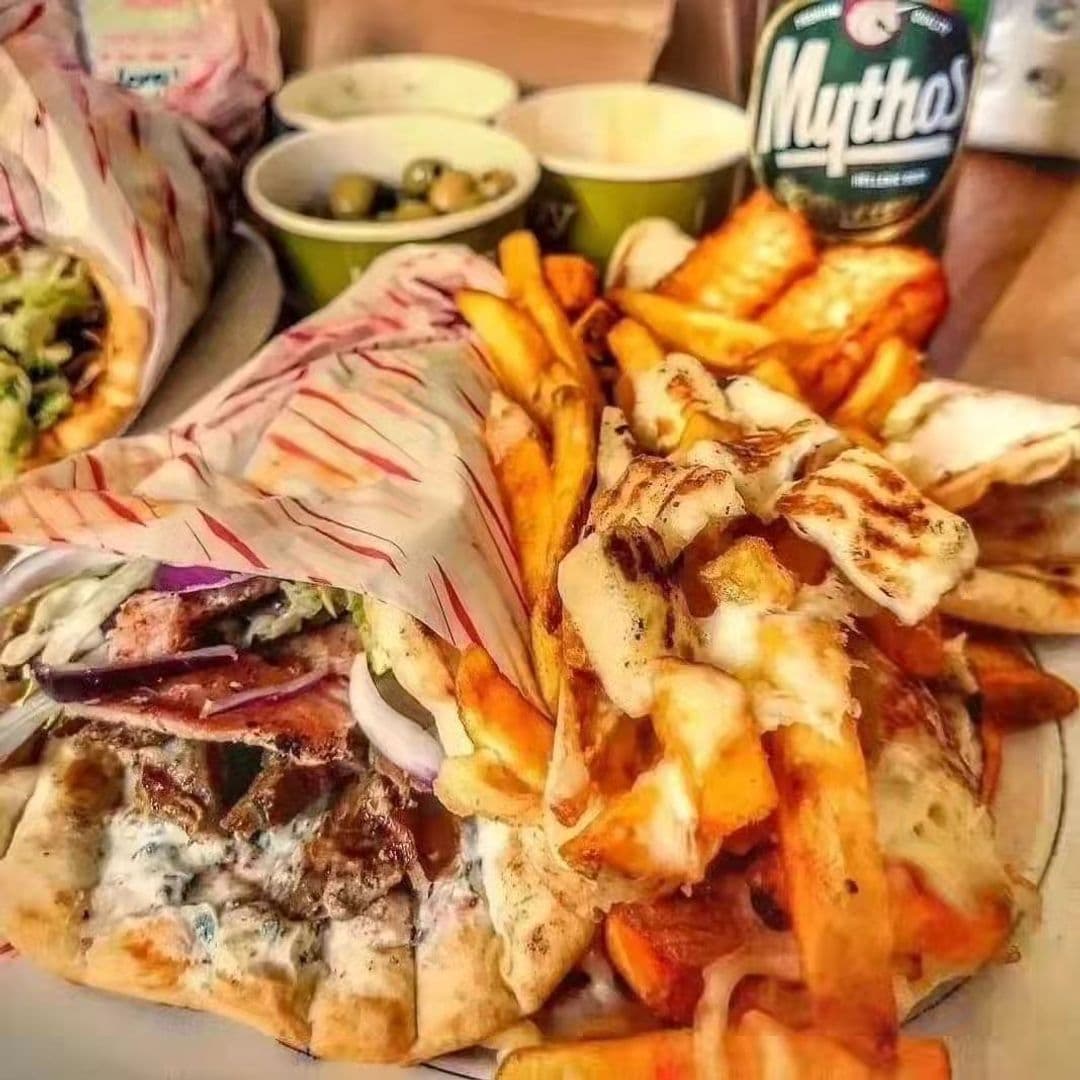 Tavassolis Cafe and Grill Greek Food Platter Gyros Fries "Savory gyro wrapped in pita with fresh toppings and tzatziki sauce, alongside golden fries and a Mythos beer at Tavassoli’s Cafe and Grill."