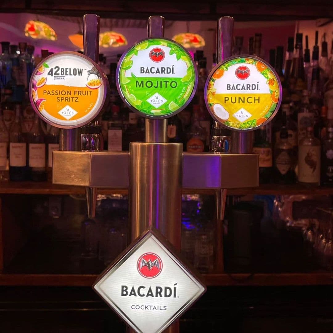 Tavassolis Cafe and Grill_Bacardi Cocktail Taps Bar Ambiance Illuminated Bacardi cocktail taps featuring Passion Fruit Spritz, Mojito, and Punch at Tavassoli's Cafe and Grill bar counter.