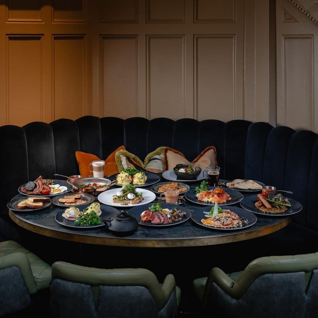 The Cut Craft Elegant Dining Experience Gourmet Meals A variety of gourmet dishes displayed on a table at The Cut & Craft, featuring a selection of meats, salads, and brunch items in an elegant dining setting with dark upholstered seating.