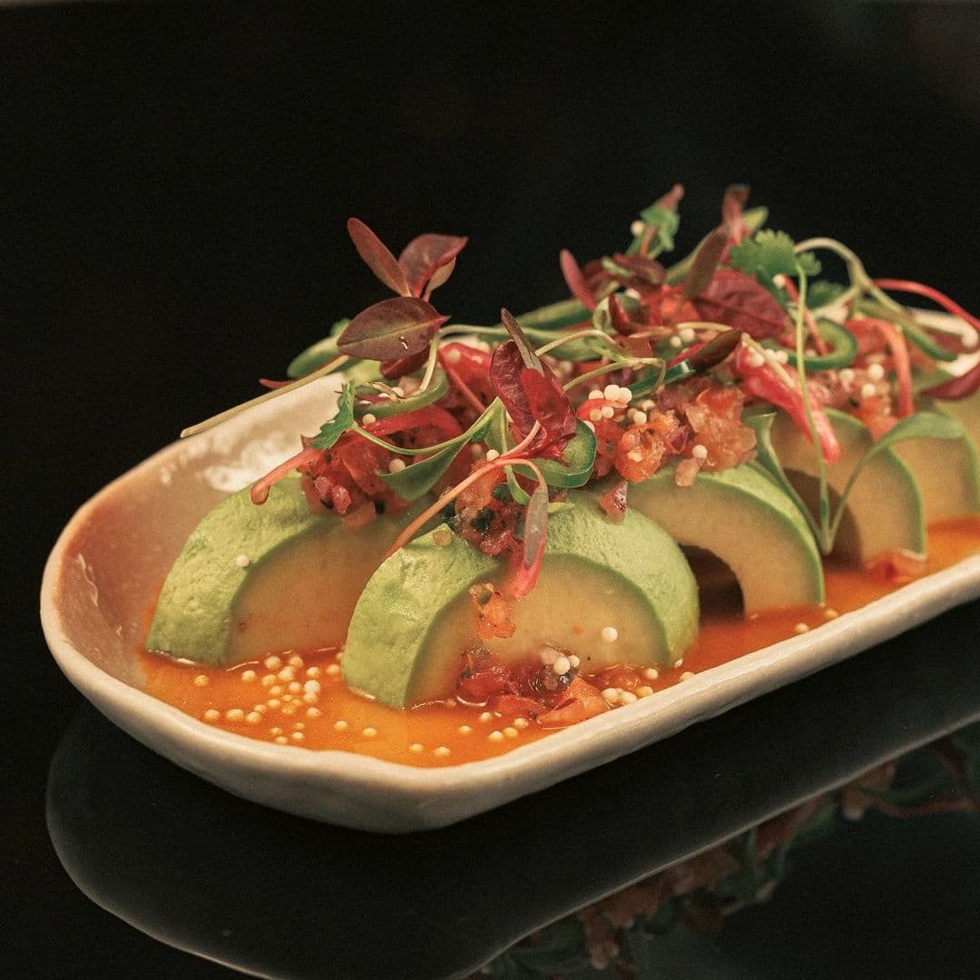 The Ivy Asia_Gourmet Avocado Dish_Fresh Herbs_Elegant Presentation Gourmet Asian-style avocado salad served at The Ivy Asia, featuring ripe avocado slices garnished with microgreens, sesame seeds, and a tangy dressing on a sleek plate.