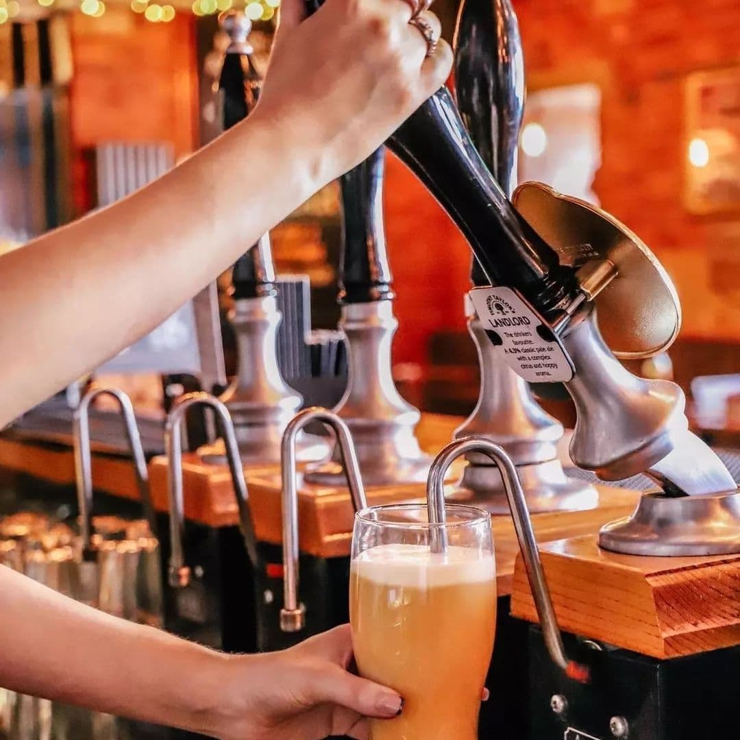 The Malt Brewhouse Pouring Craft Beer Tap Bar Atmosphere A person pouring a craft beer from a tap into a glass at The Malt Brewhouse.
