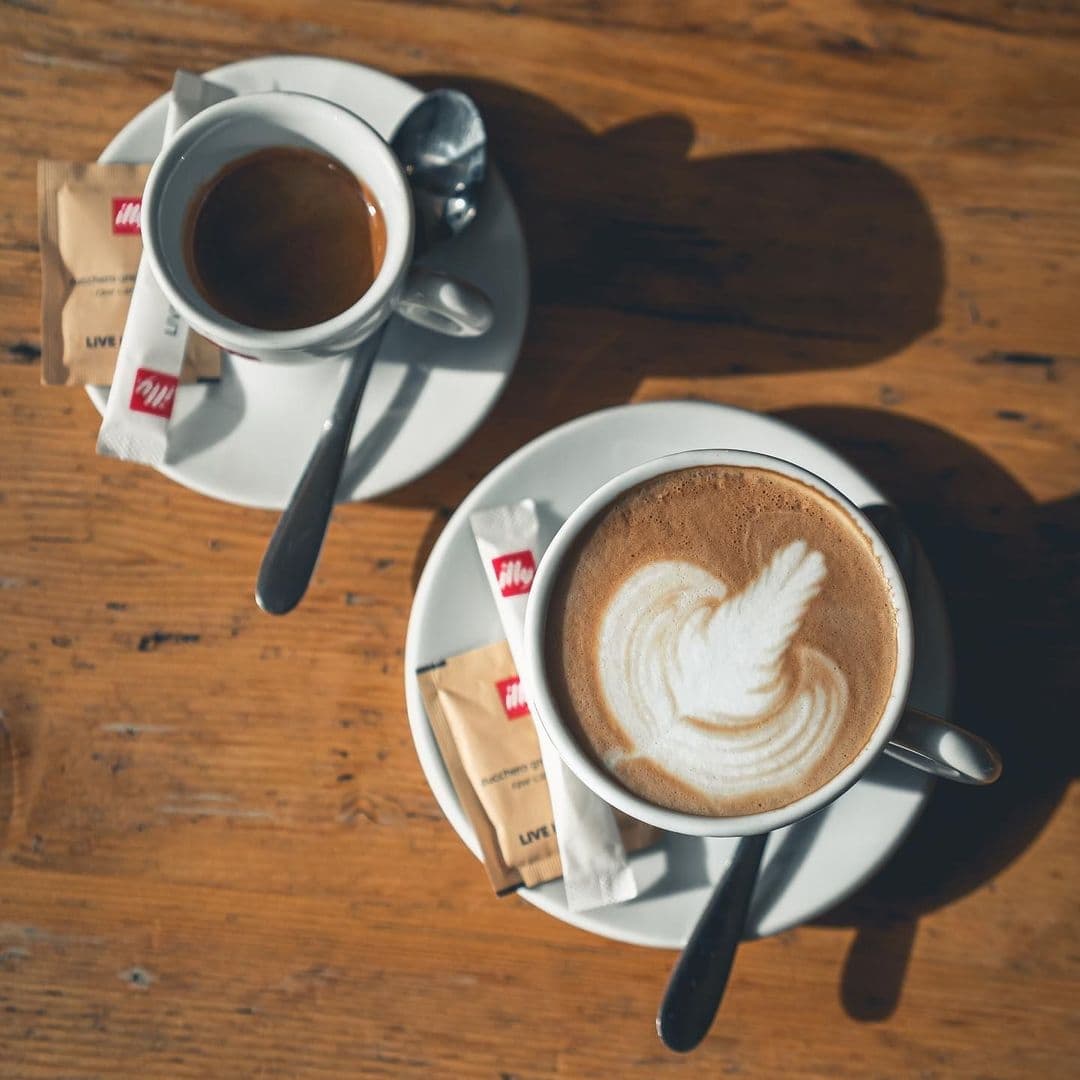 The Whitehall Restaurant & Bar_Coffee Latte Art_Wooden Table Espresso and cappuccino with latte art on a wooden table at The Whitehall Restaurant & Bar.
