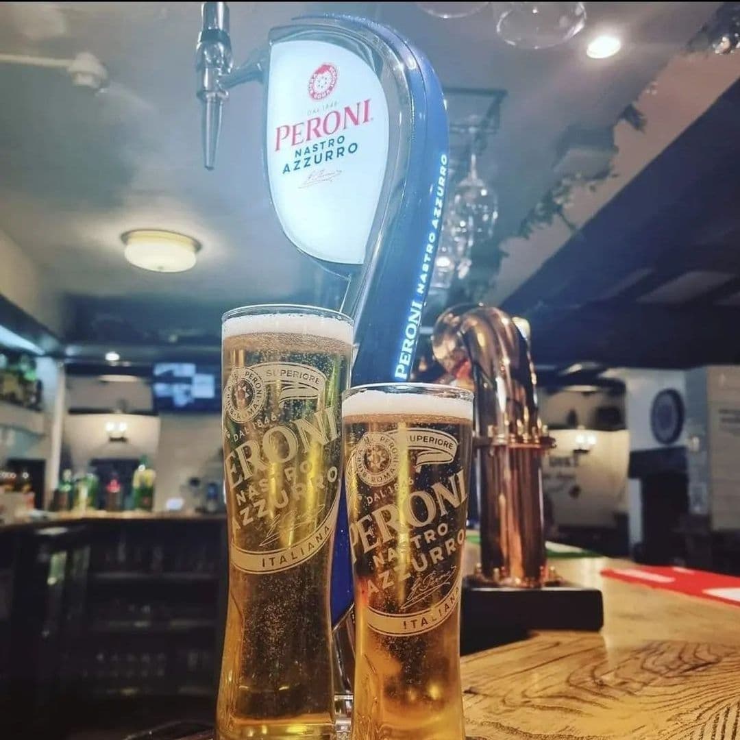 Three Horse Shoes Oulton Peroni Beer Tap Pint Glasses Two glasses of Peroni Nastro Azzurro beer on a bar counter with a beer tap in the background at Three Horse Shoes Oulton.