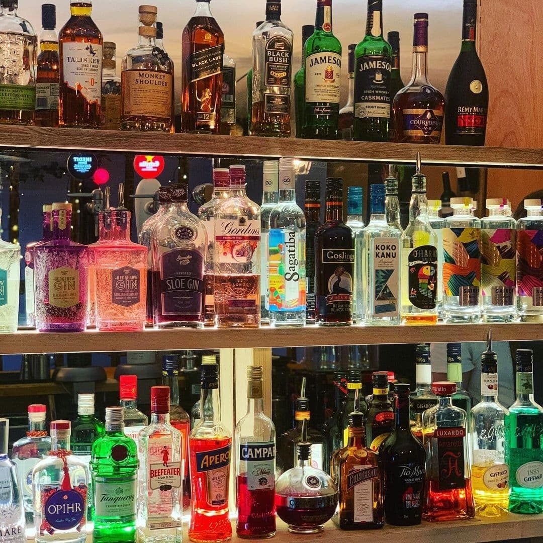 WOOD FIRE DINE Pizzeria Bar Shelves Spirits Selection Assorted liquor bottles on shelves with backlighting at WOOD FIRE | DINE Pizzeria.