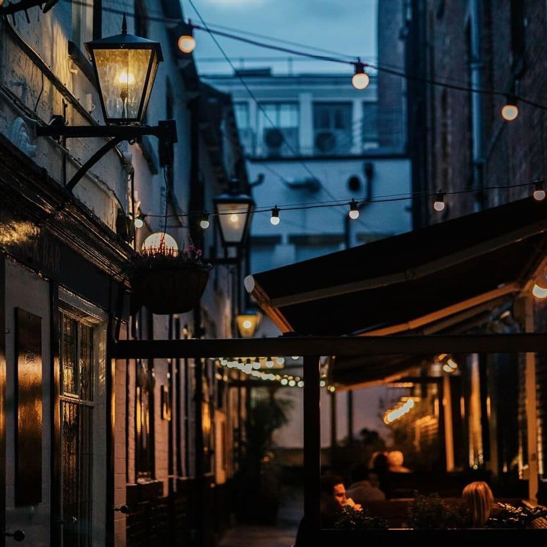 Whitelocks Ale House Evening Ambiance Outdoor Seating Evening ambiance at Whitelock's Ale House with warm lighting from hanging bulbs and a classic street lamp, patrons dining under an awning, and historic architecture in the background.