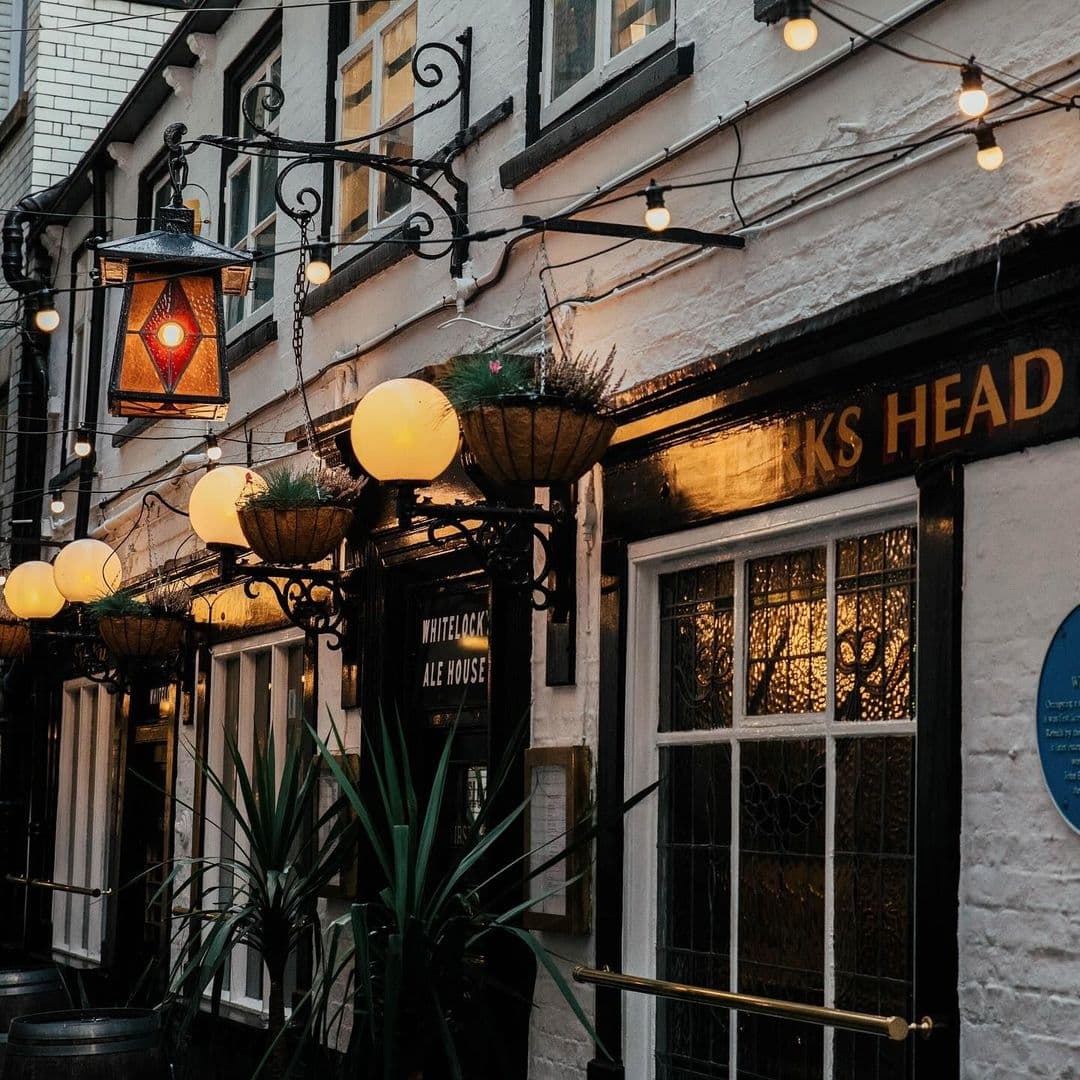 Whitelock’s Ale House Vintage Pub Exterior Evening Lights Exterior view of Whitelock's Ale House with illuminated globe street lamps and a hanging lantern above the entrance, showcasing the traditional pub facade and decorative plants.