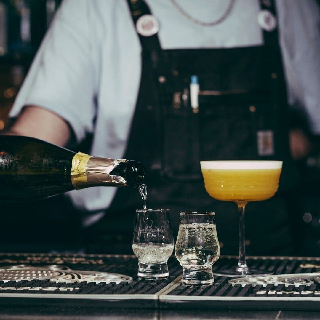 The East Village Bartender Pouring Sparkling Wine Bartender pouring sparkling wine into glasses at a bar in The East Village.