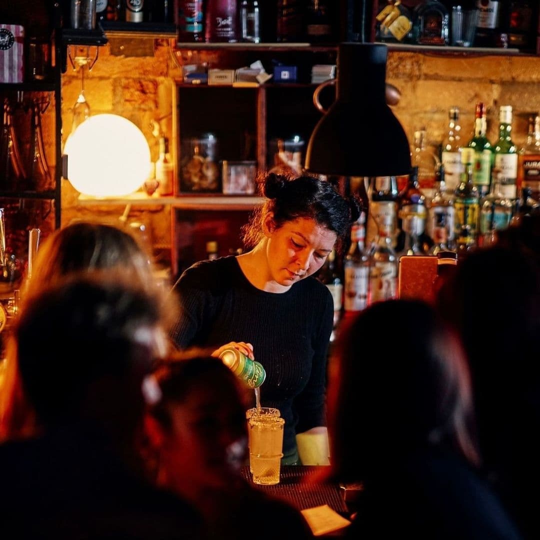 The East Village Cocktail Bar Bartender Service Bartender pouring a drink at a cozy, dimly-lit bar in The East Village.