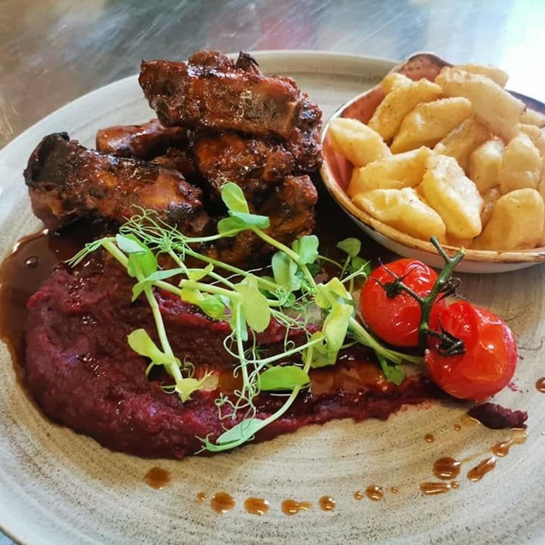 Cracovia_Taste_of_Poland_Delicious_Traditional_Cuisine Alt text: "Savor traditional Polish cuisine at Cracovia Taste of Poland with a plate of succulent grilled ribs, creamy beetroot spread, roasted cherry tomatoes, and a side of golden potato dumplings."