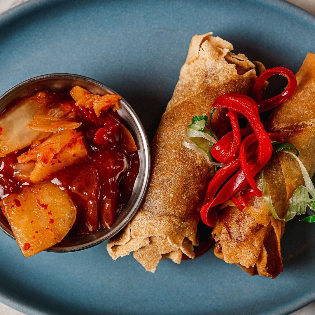 Fleur Restaurant and Bar crispy spring rolls spicy sauce Crispy spring rolls served with sweet chili sauce garnished with red pepper strips and green onions at Fleur Restaurant and Bar.