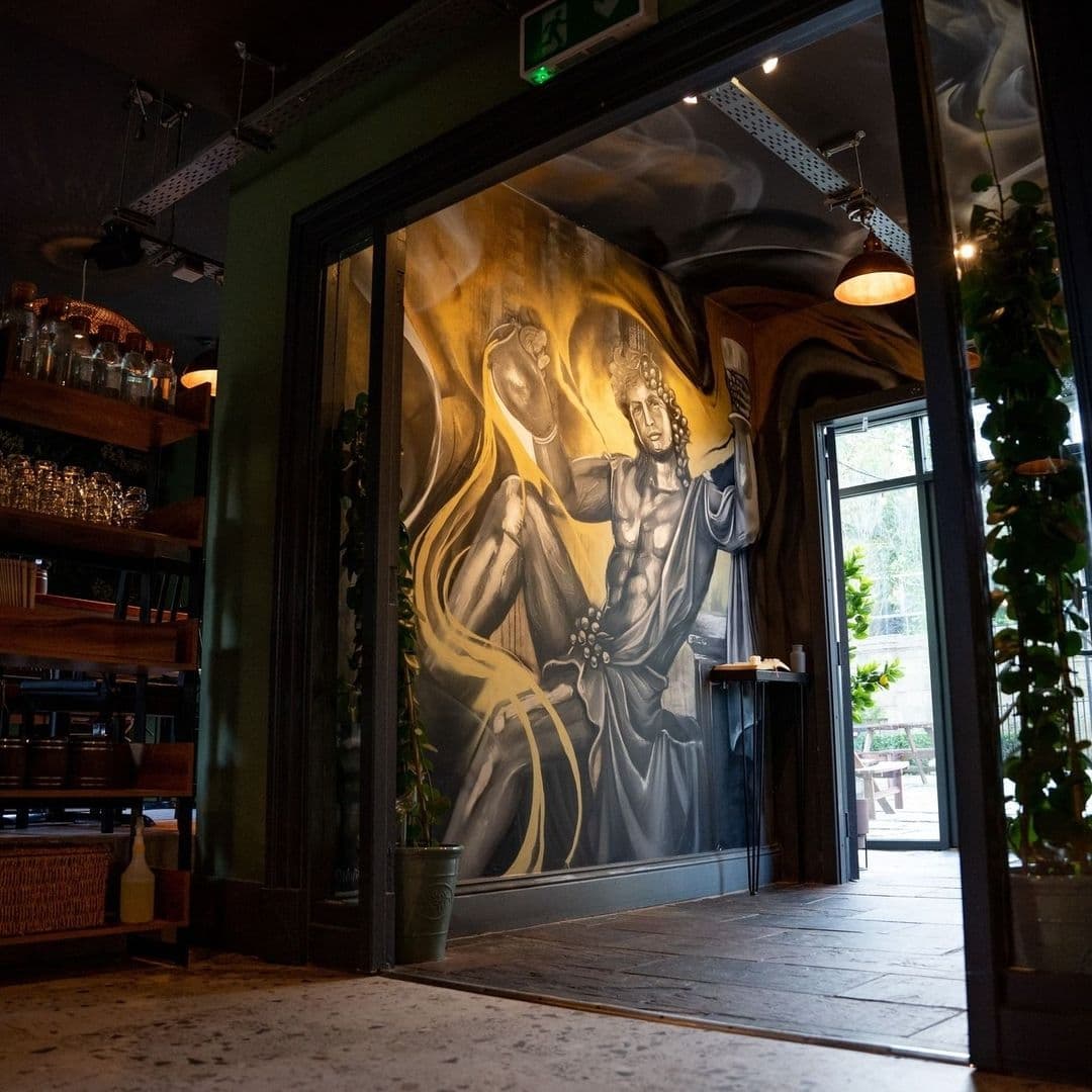 MYTHOS_Chapel_Allerton_Artistic_Mural_Interior_Decor Interior of MYTHOS Chapel Allerton featuring an artistic mural of a mythological figure, with ambient lighting and a cozy atmosphere.