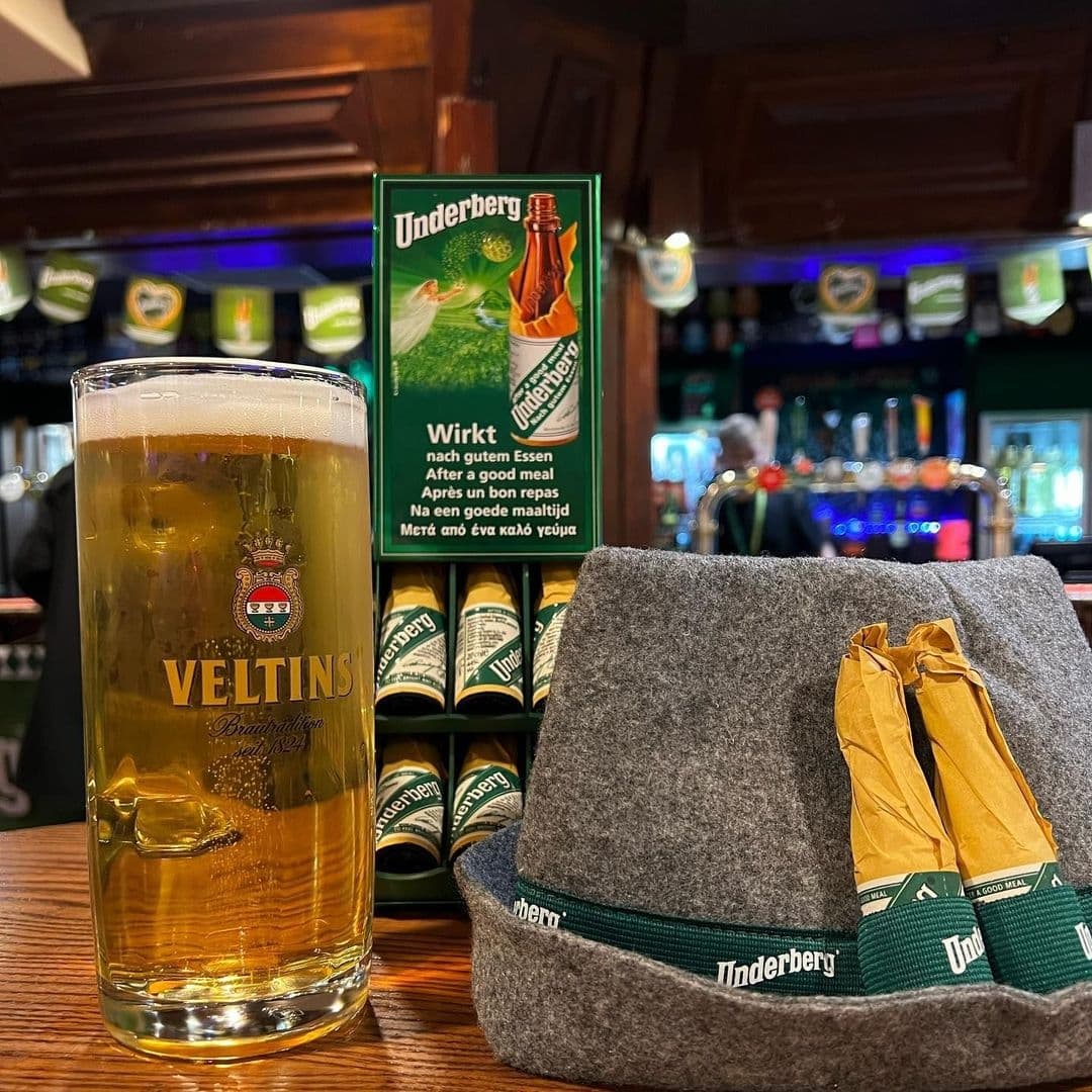 Old Bar Leeds Uni Pint Beer Underberg Hat Bar Interior A pint of Veltins beer in the foreground with Underberg digestifs and a felt hat on the bar at Old Bar – Leeds Uni.