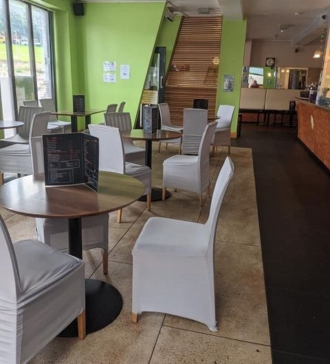 The Grand Valley Bar Kitchen Interior Modern Seating Area Interior of The Grand Valley Bar & Kitchen showing a clean and modern dining area with wooden tables, white chairs with covers, and menus on the tables. A bar counter is visible in the background.
