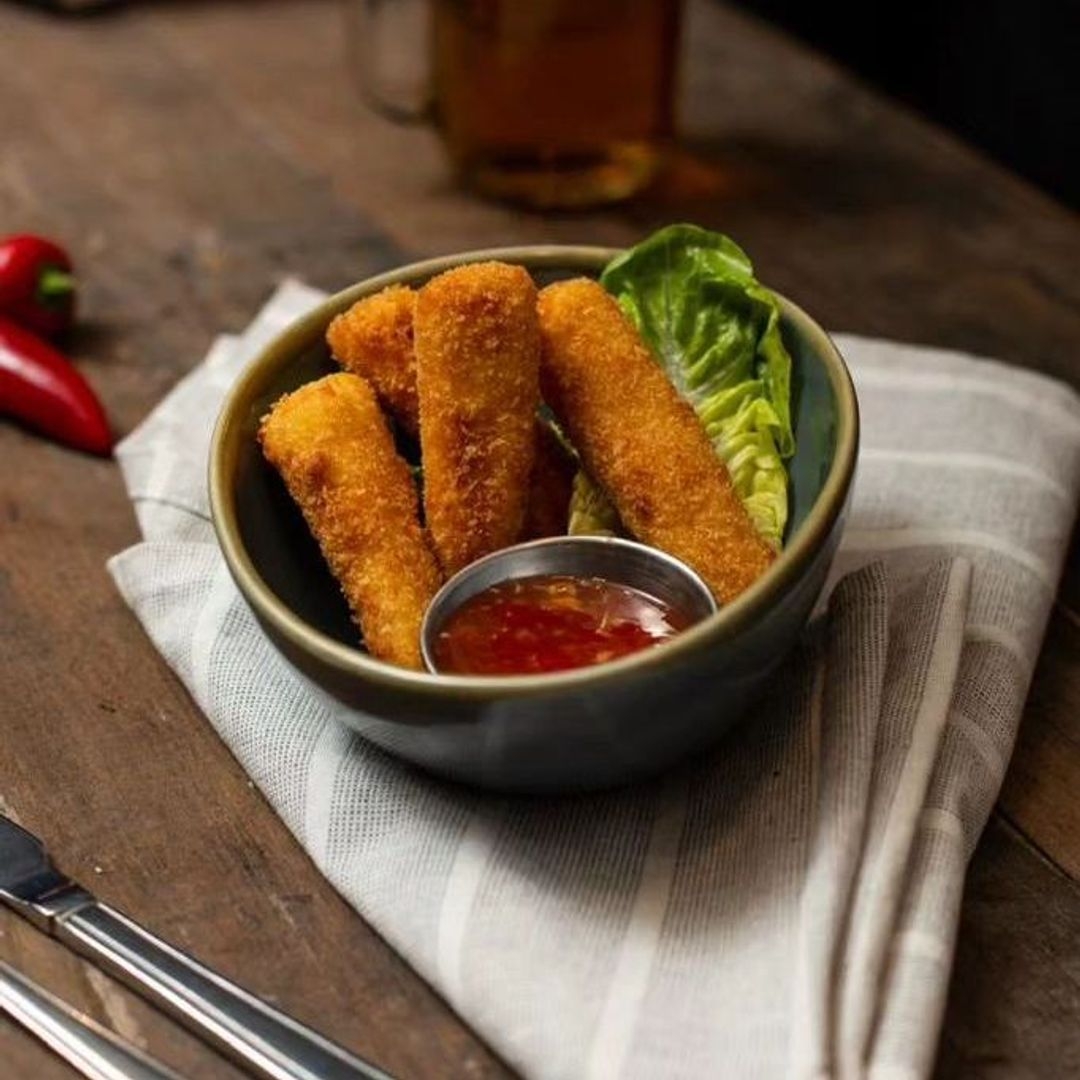 The New Conservatory Crispy Mozzarella Sticks Chili Sauce Crispy breaded mozzarella sticks served with a side of red dipping sauce at The New Conservatory.