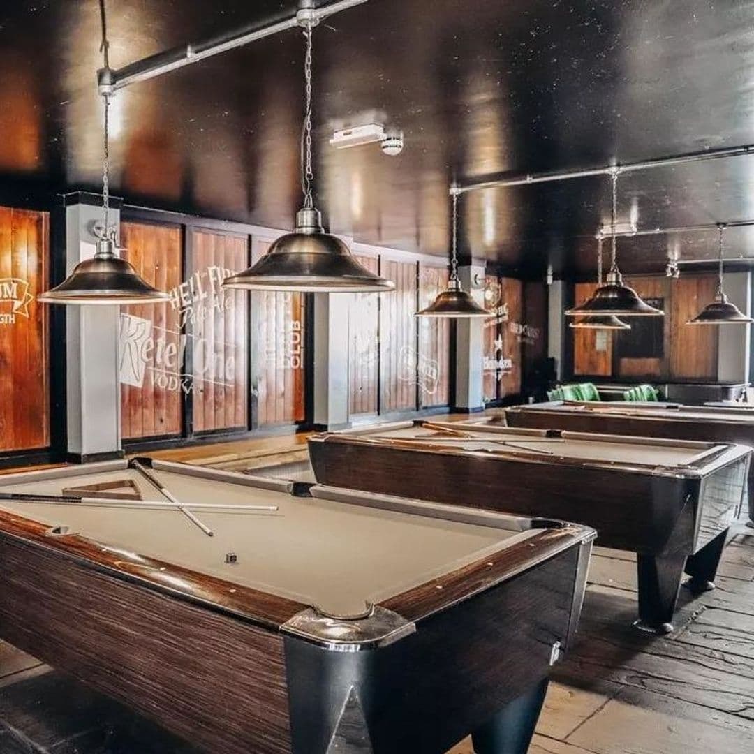 Parkside_Tavern_Industrial_Style_Pool_Tables_Interior Interior of Parkside Tavern featuring pool tables with cues, industrial-style pendant lighting, and wooden flooring.