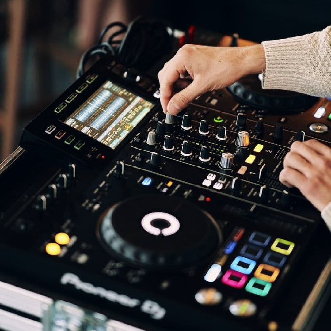 The Alchemist Trinity DJ Mixing Deck Nightlife Entertainment DJ's hand adjusting equipment at The Alchemist Trinity, showcasing a music event with a Pioneer DJ mixer and turntable in action.