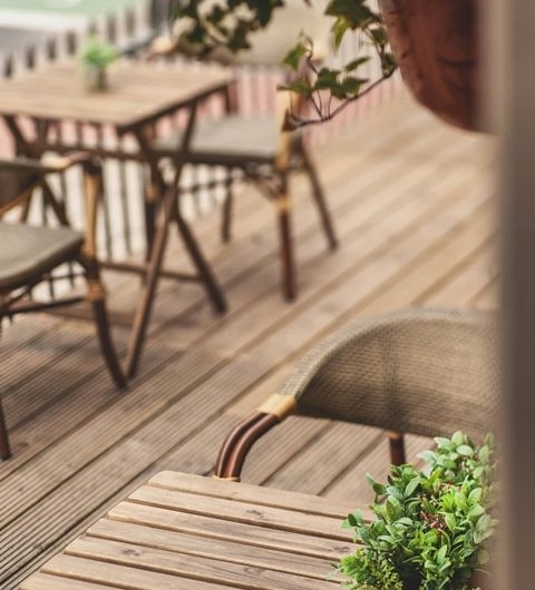 Wolfox Coffee at ZAVIYA Coffee Bar Restaurant Outdoor Seating Ambience Outdoor seating area at Wolfox Coffee at ZAVIYA COFFEE Bar & Restaurant featuring wooden tables and chairs on a deck with green plants.