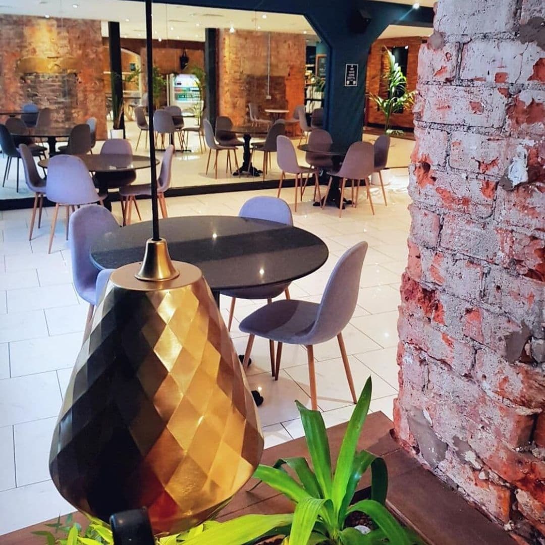 Wolfox_Coffee_at_ZAVIYA_COFFEE_Bar_Restaurant_Stylish_Interior_Brick_Walls_Modern_Decor Interior of Wolfox Coffee at ZAVIYA COFFEE Bar & Restaurant showcasing modern tables and chairs with exposed brick walls and elegant lighting.