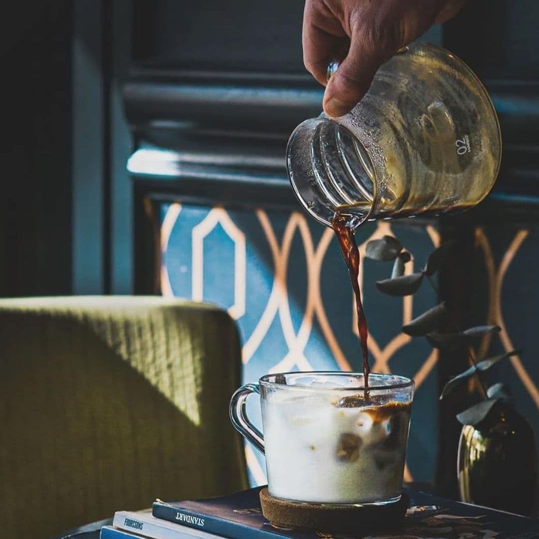 Wolfox_Coffee_at_ZAVIYA_Coffee_Bar_Restaurant_Pouring_Fresh_Brew_Ambient_Interior "Hand pouring a rich espresso shot into a creamy iced latte at Wolfox Coffee at ZAVIYA COFFEE Bar & Restaurant, with elegant interior decor in the background."