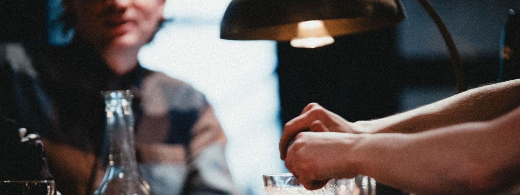 Intimate ambiance at Below Stairs with a close-up of clasped hands over a table, under warm lighting.
