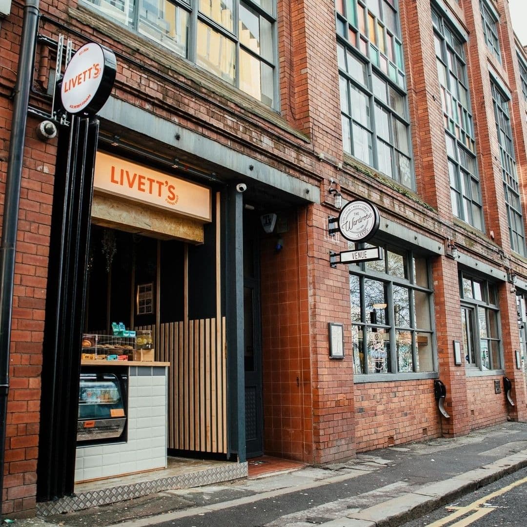 Livetts Coffee Shop Brick Building Entrance Street View Exterior view of Livett's Coffee Shop with a prominent orange sign, nestled in a brick building with large windows and a vintage vibe.