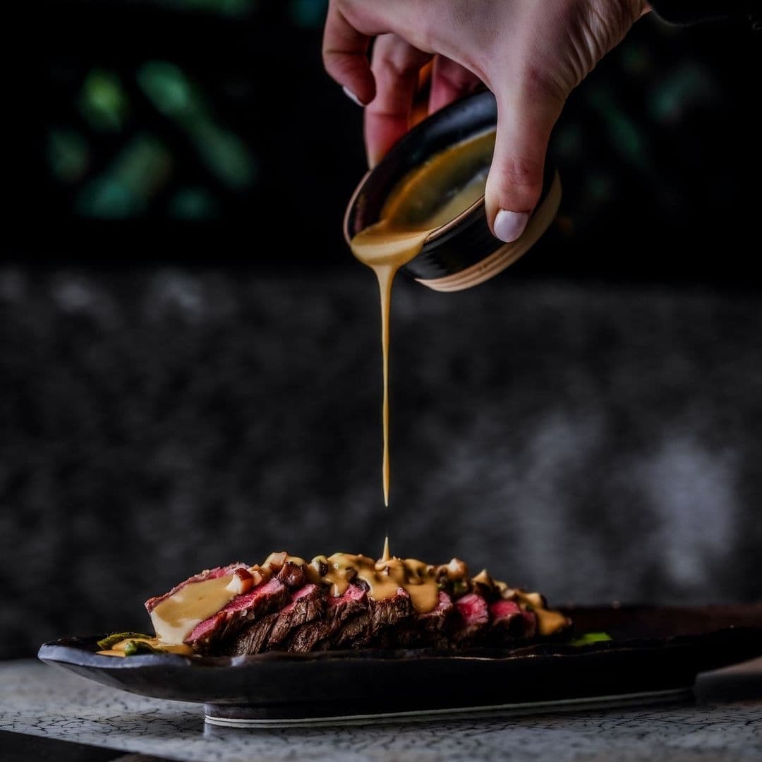 Tattu_Gourmet_Steak_Pouring_Sauce "Succulent sliced steak being served with a drizzle of sauce at Tattu restaurant."