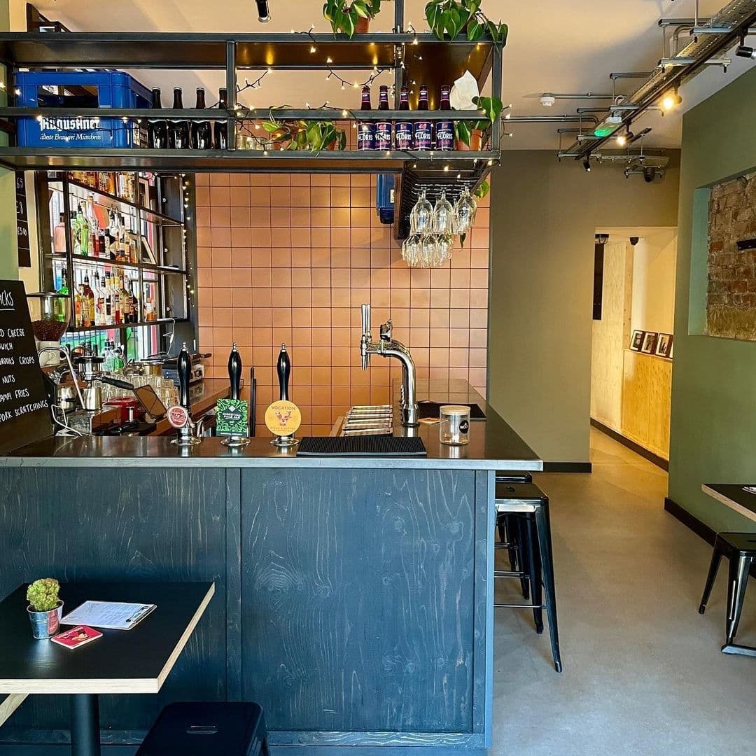 TheMelbourne_CozyBarInterior_CraftBeers_StylishDecor Interior of The Melbourne bar with a well-stocked counter, beer taps, and comfortable seating area.