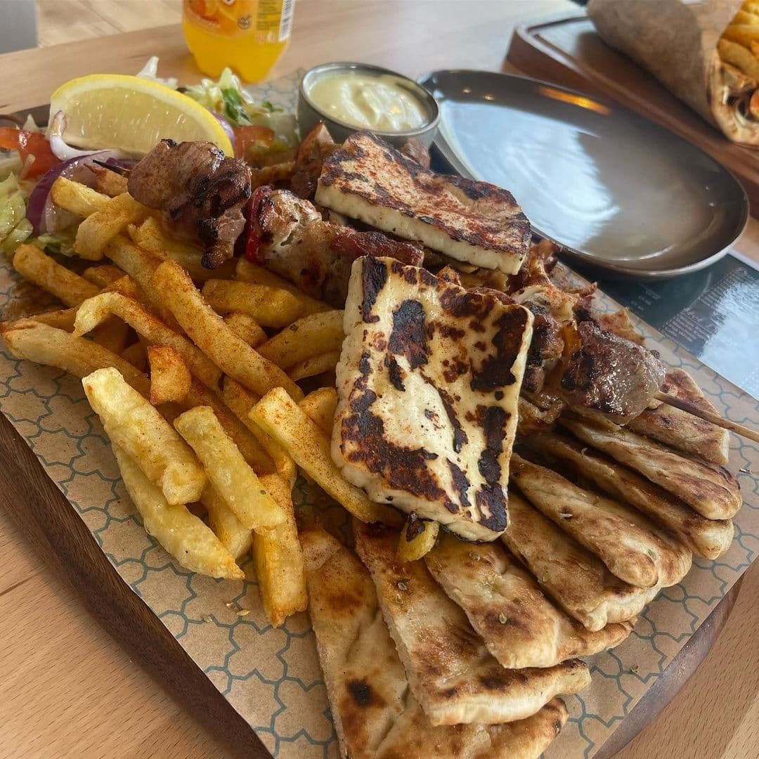 The Med Greek Street Food Grilled Meat Platter Fries Tzatziki Platter of Greek cuisine featuring skewered meat, fries, pita bread, and grilled cheese at The Med Greek Street Food restaurant.