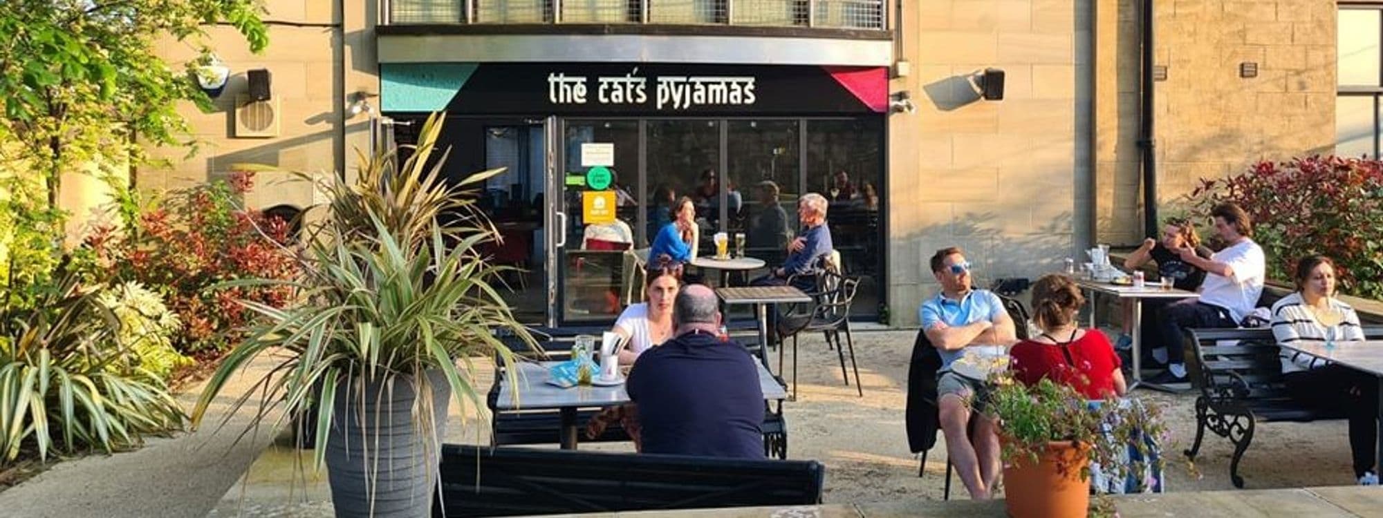 Outdoor seating at The Cat’s Pyjamas – Chapel Allerton with patrons enjoying meals and drinks in the sunshine.