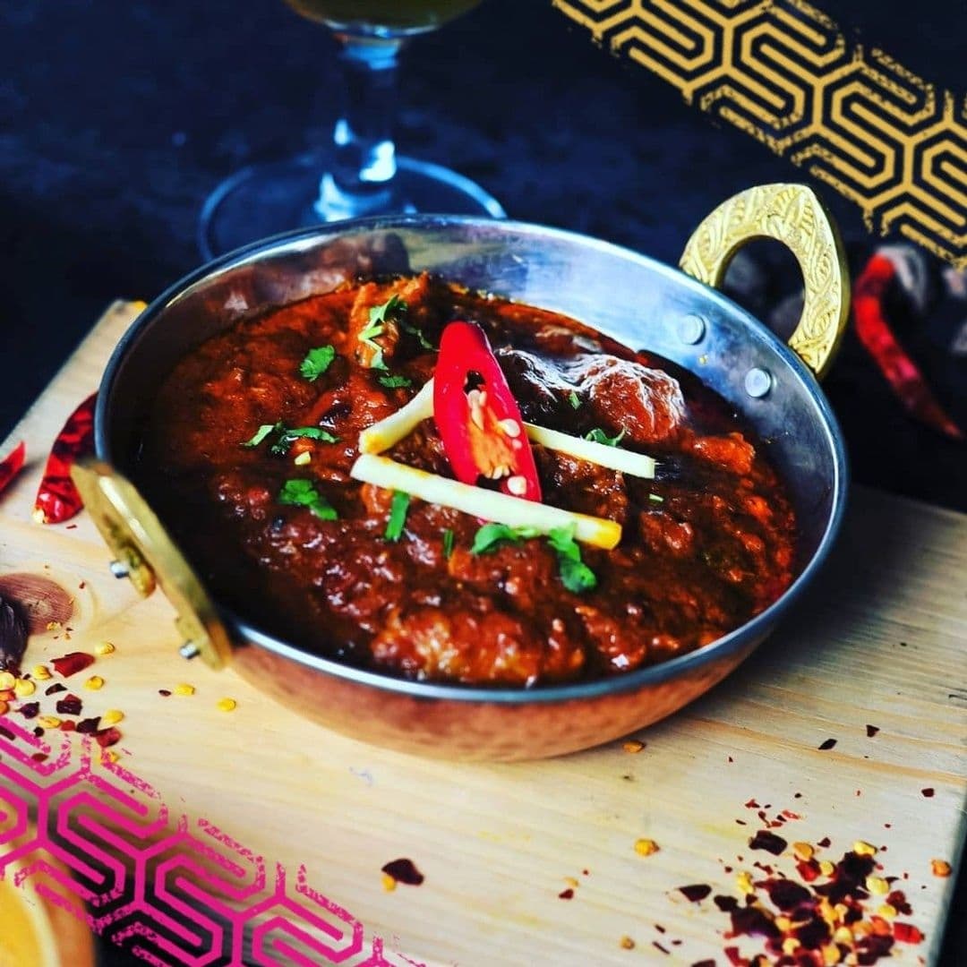 The Cats Pyjamas Chapel Allerton Spicy Curry Dish Decorated Savory curry dish garnished with fresh herbs and chili, served in a metal bowl at The Cat’s Pyjamas – Chapel Allerton.