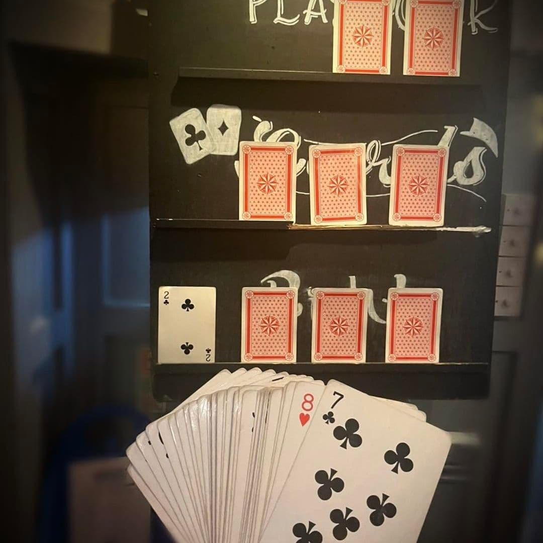 The Thornhill Playing Cards Magic Trick Entertainment Alt text: "Magic-themed entertainment at The Thornhill featuring playing cards displayed in an intriguing arrangement on a dark wall, with a fan of cards in the foreground suggesting a card trick or game."