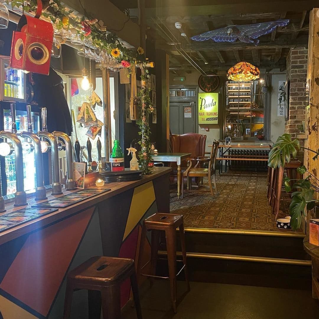 Doghouse Bar Bagel Shop Cozy Eclectic Interior Decor Interior of Doghouse Bar & Bagel Shop showing a cozy setting with a bar counter, beer taps, eclectic decorations, and vintage-style furniture.