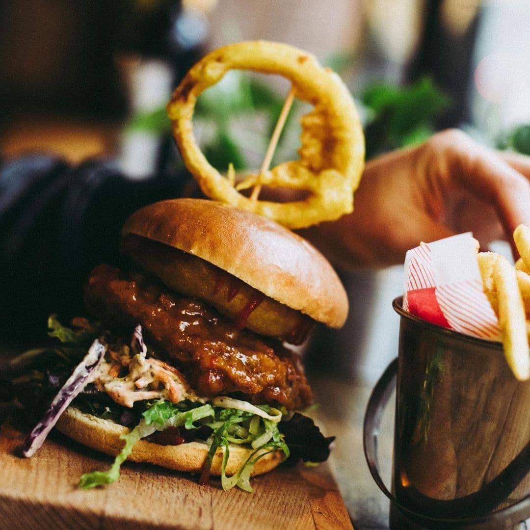 The Old Red Bus Station Gourmet Burger Onion Ring Fries Gourmet burger with crispy onion ring and side of fries served at The Old Red Bus Station.