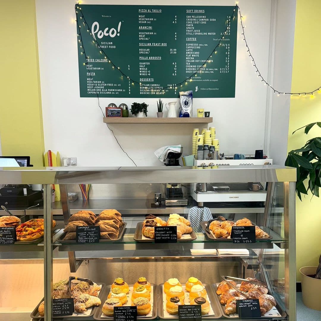 POCO Sicilian Street Food The Calls Delicious Pastries Display Interior of POCO Sicilian Street Food – The Calls, showing a display counter with various pastries and bread, a menu board on the wall, and a coffee machine area.