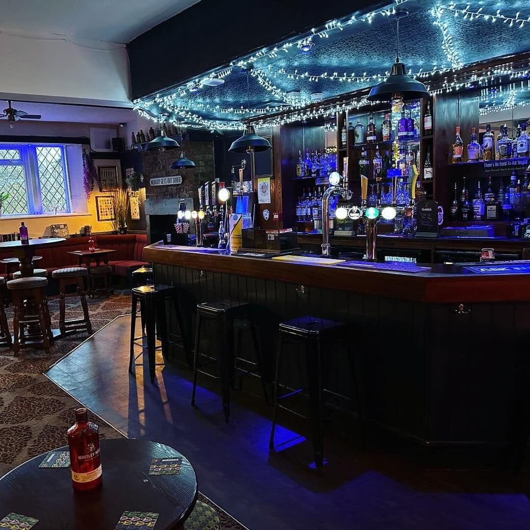 The Commercial Cozy Pub Interior Twinkle Lights Bar Counter Interior of The Commercial showing a cozy pub atmosphere with a well-stocked bar, bar stools, and traditional seating areas under decorative string lights.