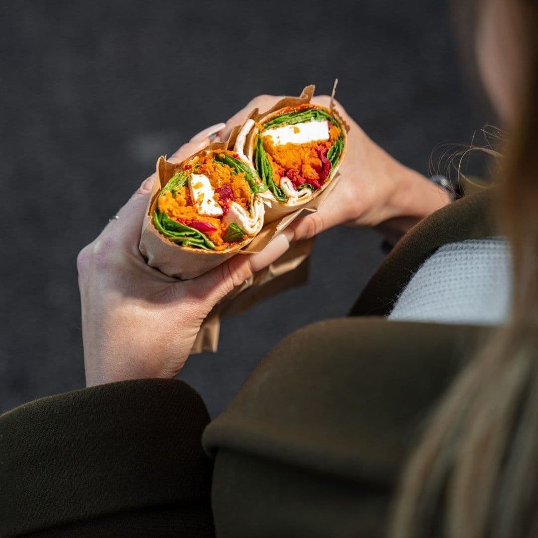 200 Degrees Coffee Shop delicious wraps fresh healthy lunch Two delicious wraps filled with colorful ingredients, including greens, roasted vegetables, and creamy sauce, held in a person's hands. The setting is casual, perfect for enjoying a meal at 200 Degrees Coffee Shop.