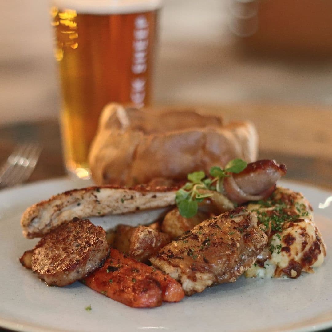 Convive Restaurant gourmet dish beer platter dining experience Delicious plate of assorted meats and vegetables served at Convive Restaurant, featuring grilled chicken, sausages, and roasted carrots, accompanied by a pint of beer and a Yorkshire pudding.