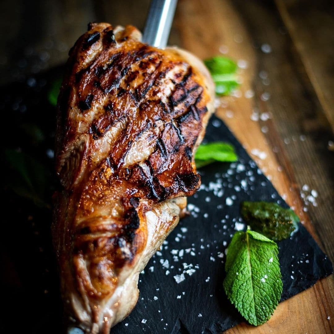 Fazenda Bar Grill grilled meat restaurant dining delicious Grilled meat served on a slate plate, garnished with fresh mint leaves and sprinkled with coarse salt. The image showcases a delicious dish from Fazenda Bar & Grill, highlighting the restaurant's focus on high-quality grilled cuisine.