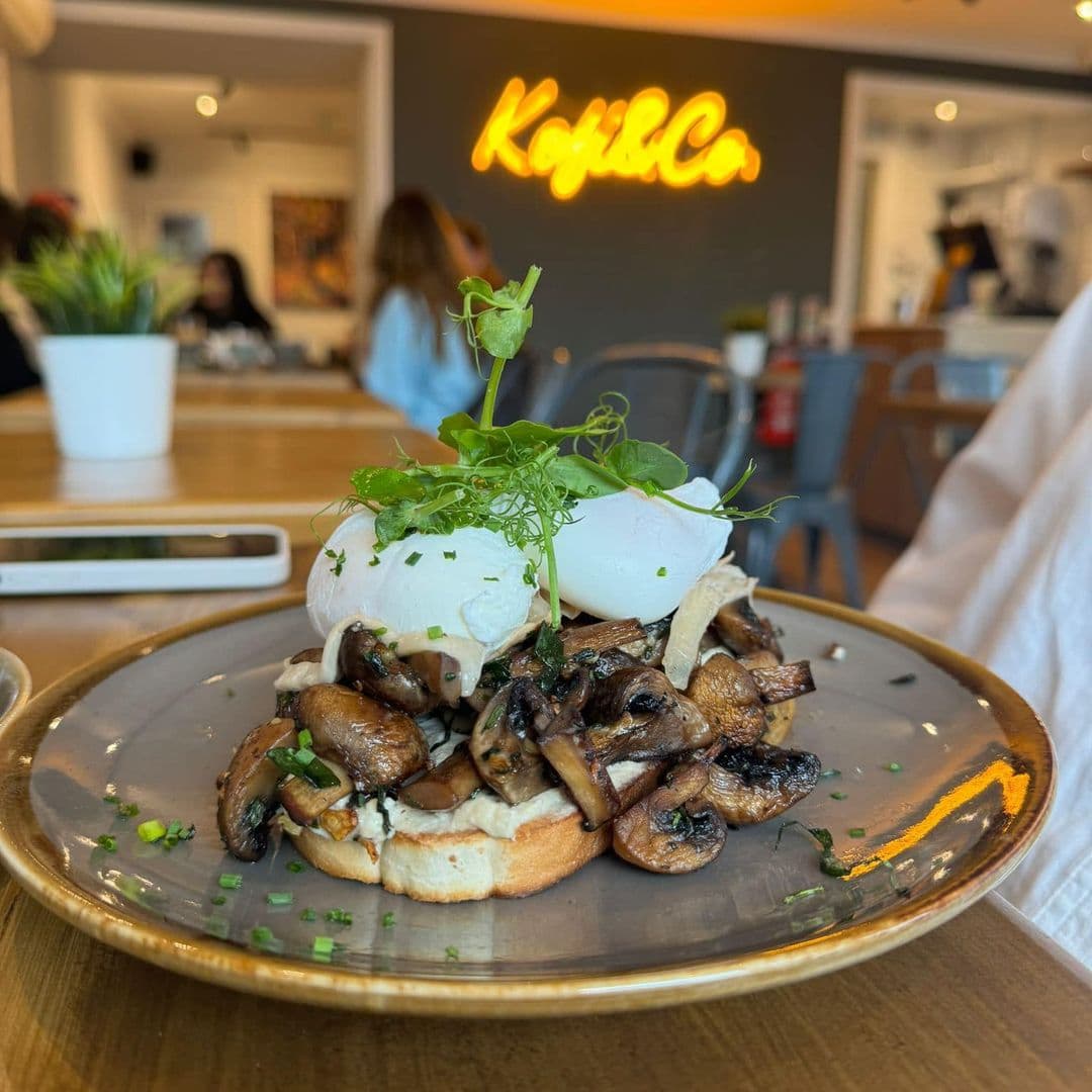 Kofi Co Wetherby poached eggs mushrooms brunch restaurant Alt text: A delicious plate of poached eggs on toasted bread topped with sautéed mushrooms and fresh herbs, served at Kofi&Co – Wetherby.