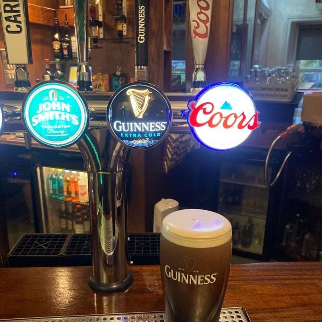 New Inn Yeadon Alt text: A close-up view of a bar counter at New Inn – Yeadon, featuring three beer taps with illuminated logos for John Smith's, Guinness Extra Cold, and Coors. A freshly poured pint of Guinness sits in the foreground.