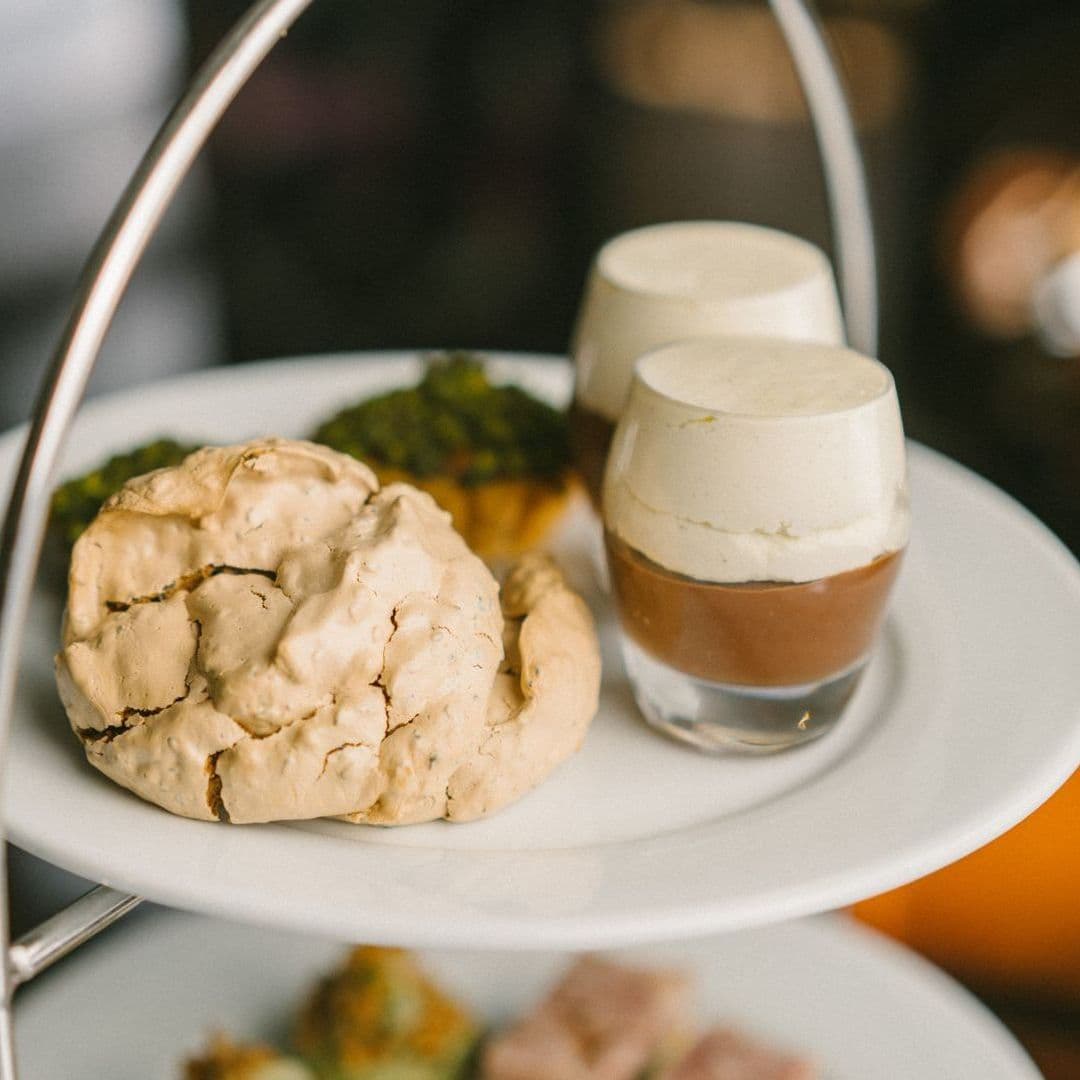 Terrace Tearoom afternoon tea desserts gourmet treats Delicious desserts served on a tiered platter at the Terrace Tearoom, featuring a large meringue, two small dessert cups with layered chocolate and cream, and a piece of pastry topped with green toppings.