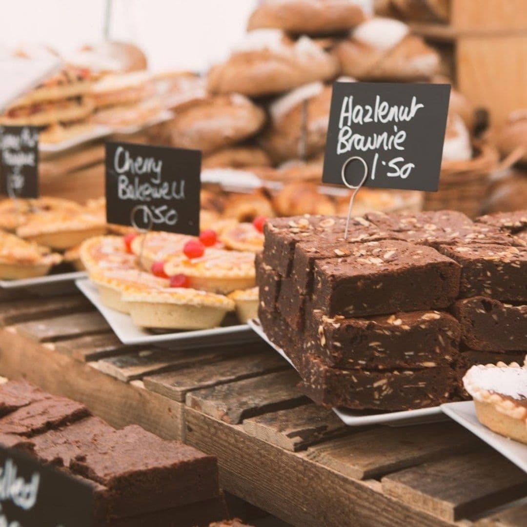 Terrace Tearoom bakery treats desserts fresh baked goods Delicious baked goods displayed at the Terrace Tearoom, featuring a variety of treats including hazelnut brownies and cherry bakewells, all labeled with prices. The setting has a rustic wooden table, enhancing the cozy atmosphere.