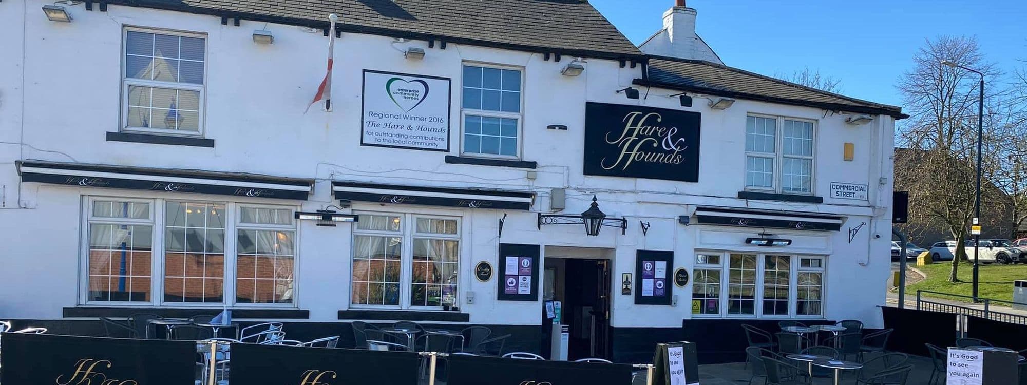 The Hare and Hounds – Rothwell, a charming pub with a welcoming facade, features large windows and a prominent sign. Outdoor seating is available, inviting guests to enjoy the surroundings. The building is well-maintained, showcasing a blend of traditional and modern elements.