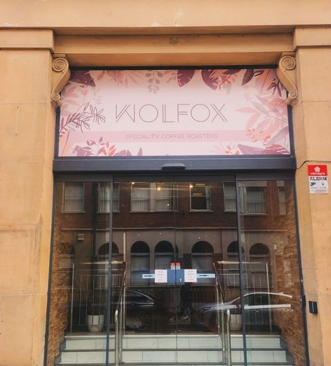 Wolfox Coffee Speciality Roasters Cafe Entrance Exterior Entrance of Wolfox Coffee, featuring a stylish sign with the name "WOLFOX" and the tagline "SPECIALITY COFFEE ROASTERS." The storefront has large glass doors and decorative elements, inviting visitors to enjoy quality coffee.