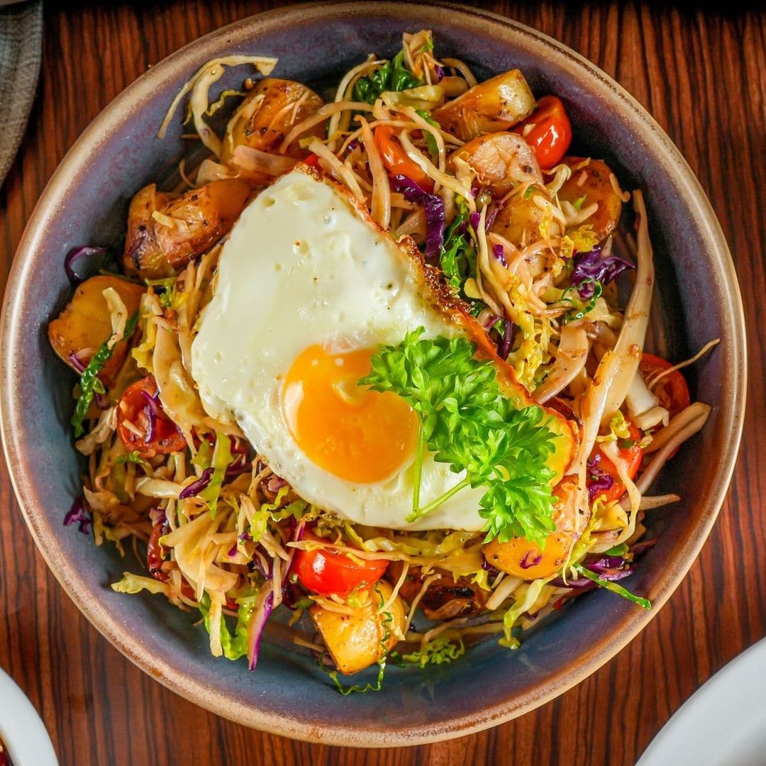Wolfox Coffee delicious bowl food gastronomy cuisine Bowl of colorful stir-fried noodles topped with a sunny-side-up egg and fresh parsley, served at Wolfox Coffee.