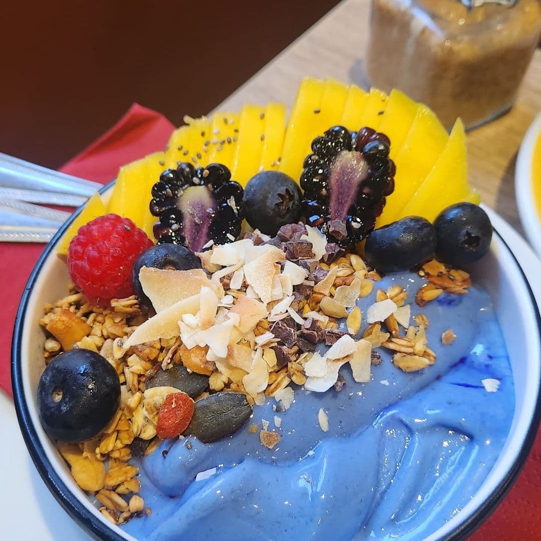 Wolfox Coffee fruit bowl healthy breakfast delicious dessert A colorful bowl of smoothie topped with sliced mango, blackberries, blueberries, raspberries, and granola at Wolfox Coffee. The vibrant presentation highlights fresh fruits and crunchy toppings, making it an appealing choice for a healthy snack.