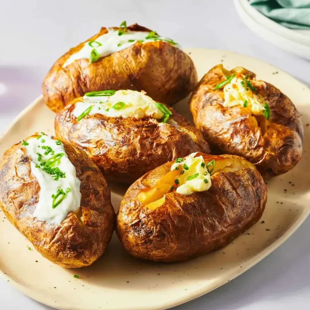 Scoffs Feel Good Food baked potatoes delicious creamy chives Baked potatoes topped with sour cream and chives served on a beige plate at Scoffs Feel Good Food.