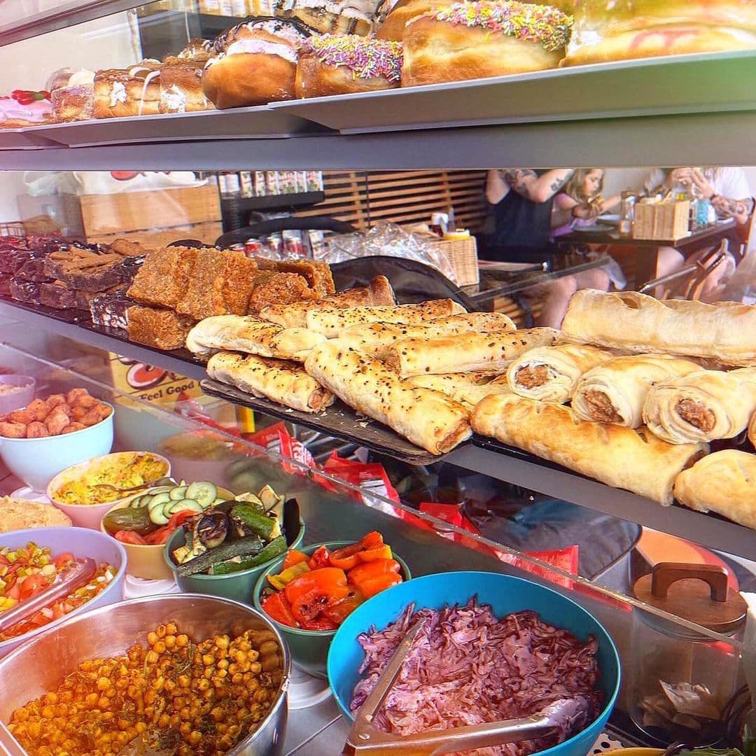 Scoffs Feel Good Food delicious dishes bakery fresh ingredients A colorful display of various delicious foods at Scoffs Feel Good Food. The image showcases an assortment of baked goods, including donuts with sprinkles, savory pastries, and a variety of fresh salads and sides in bowls. The vibrant presentation highlights the inviting atmosphere of the eatery.