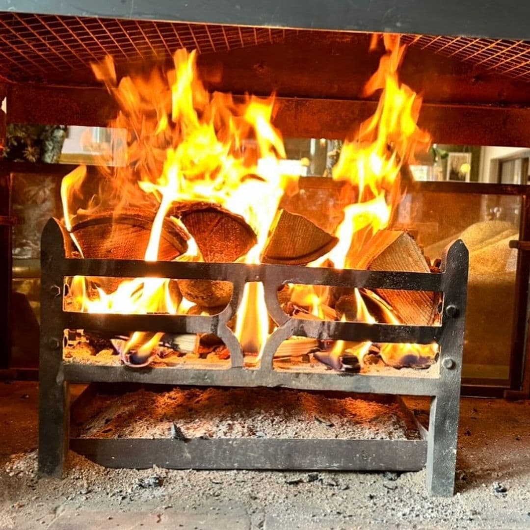 Deer Park Hotel cozy fireplace warmth relaxation hospitality A cozy fireplace with bright flames and stacked logs at Deer Park Hotel, creating a warm and inviting atmosphere.